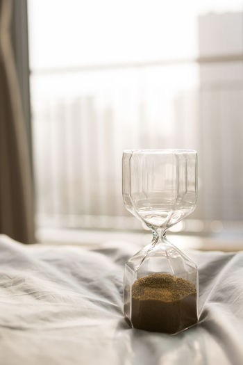 Close-up of hourglass on bed at home