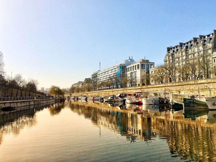 Buildings and boats reflection on seine river against clear sky in paris 