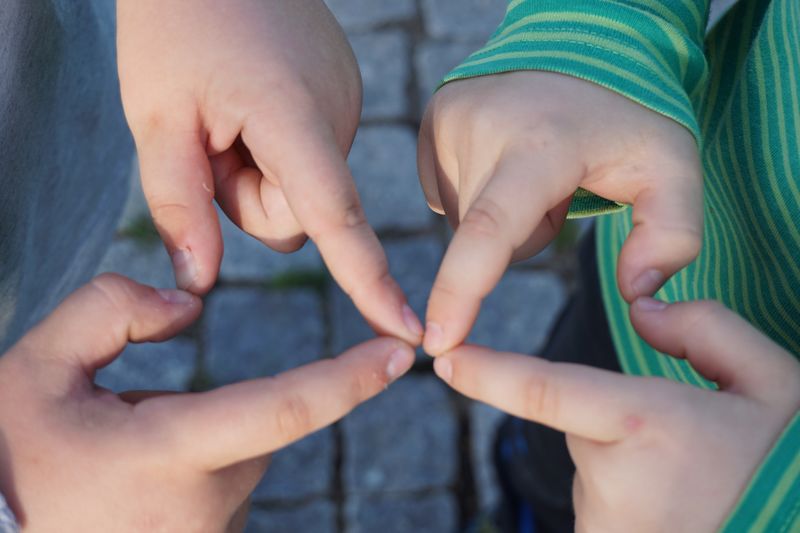 Close-up of boys hands making heart shape outdoors