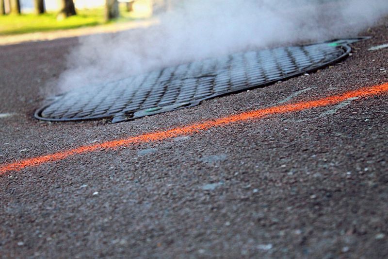 Close-up of steam from manhole lid on road