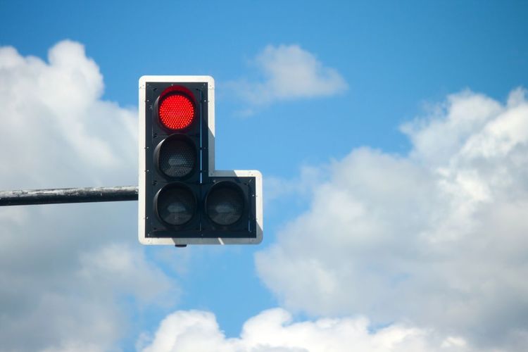Low angle view of traffic signal against cloudy sky