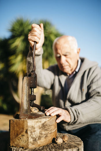 Senior man using an old tool for cracking walnuts