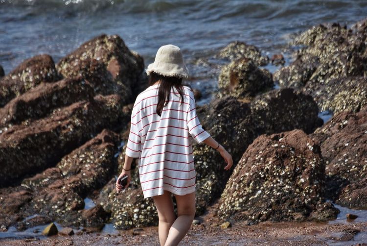 Rear view of woman wearing hat walking at beach