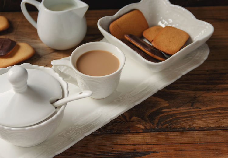Coffee cup and cookies on a tray on wooden table close up
