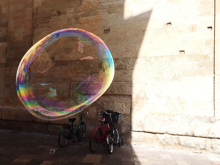 Big bubble in mid-air by bicycle parked against wall