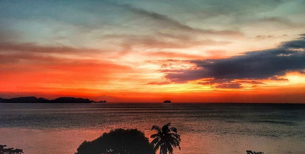 Scenic view of sea against dramatic sky during sunset