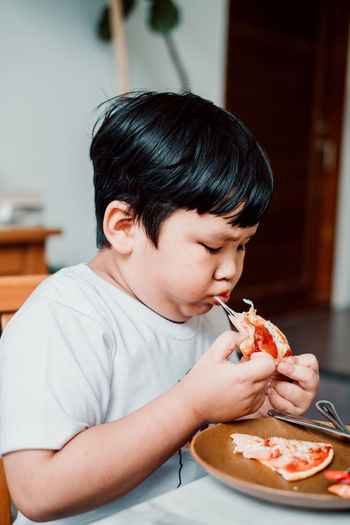 Cute boy eating food at home