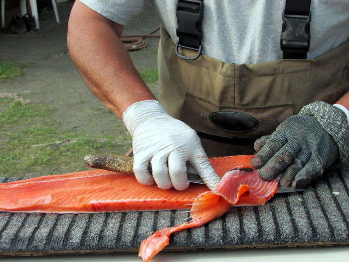 Midsection of man filleting fish at market