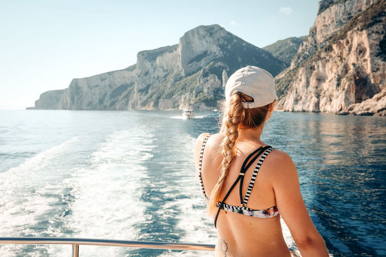 Woman in bikini by sea against mountain