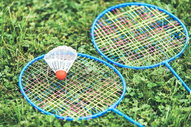 Close-up of badminton rackets with shuttlecock on grassy field