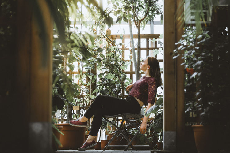 Side view of woman sitting on chair in yard