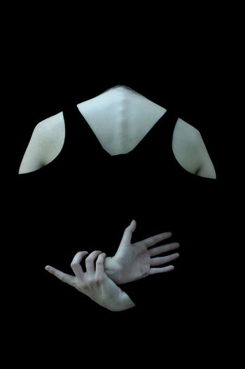 Rear view of woman with hands behind back against black background