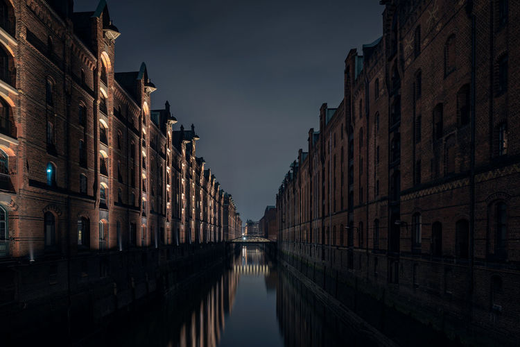 Canal amidst buildings against sky at dusk
