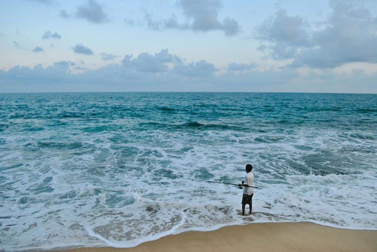 High angle view of fisherman fishing on beach against sky