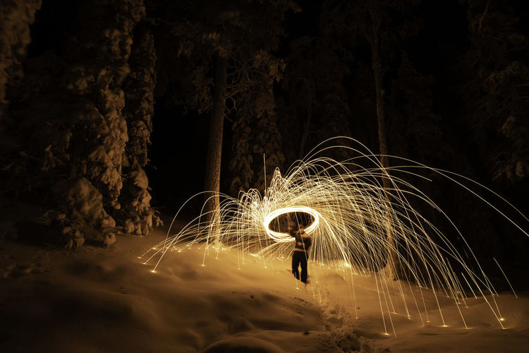 Man with wire wool on snow covered landscape at night