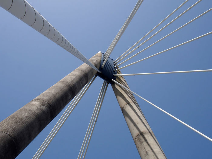 A close up of the supports and cables of the suspension bridge in southport against a blue sky