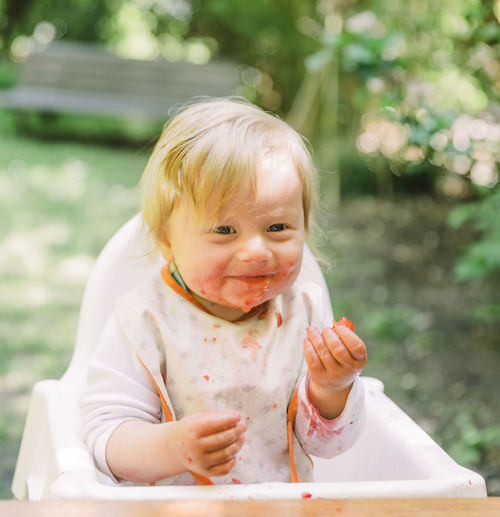 Portrait of cute boy eating food while sitting outdoors