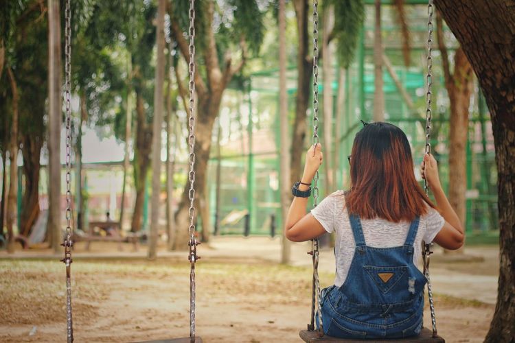 Woman sitting on swing in playground