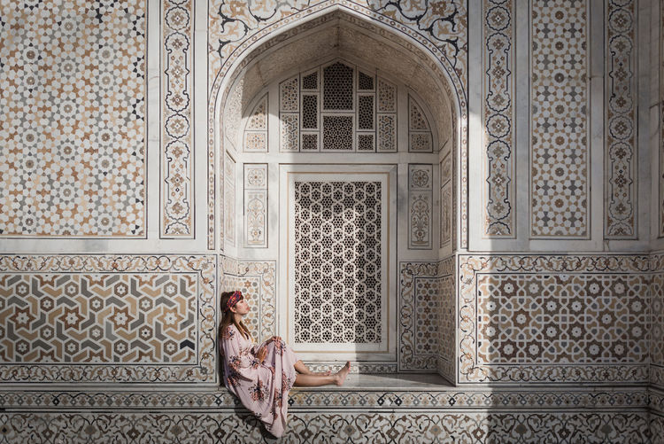 Woman sitting on window sill of historic building