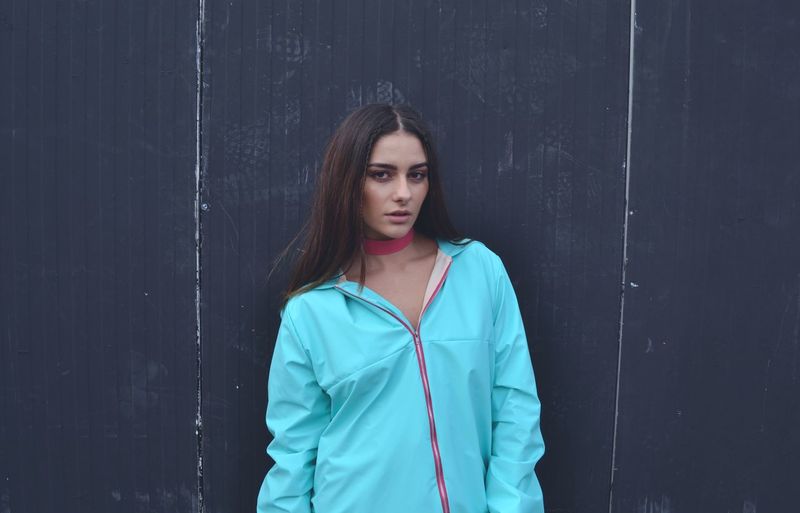 Portrait of young woman standing against wall