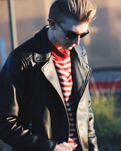 Young man wearing leather jacket while standing outdoors