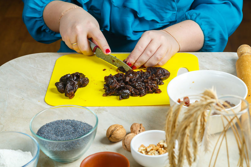 Women's hands make prunes filling for poppy-seed gomentashi cookies, traditional for the jewish 