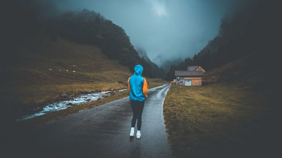 Rear view of woman walking on road against sky