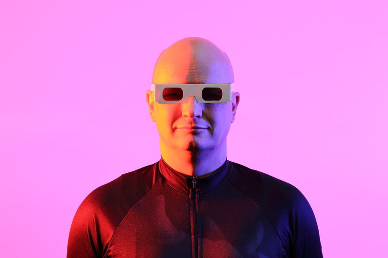 Man wearing 3-d glasses against pink background