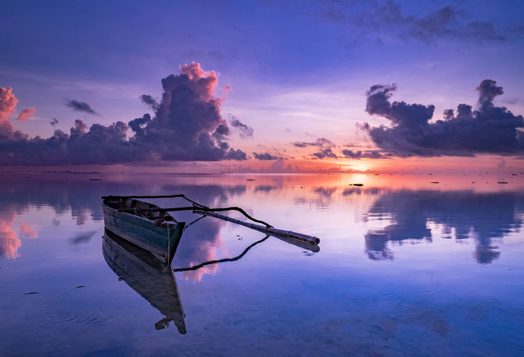 Boat moored in sea against sky during sunset