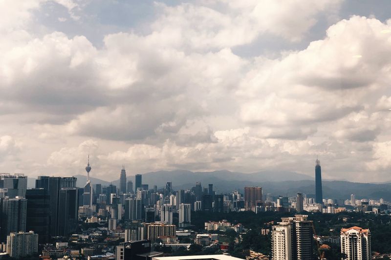 Aerial view of modern buildings against cloudy sky in city