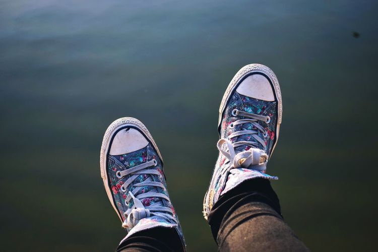 Low section of woman wearing shoes against sea