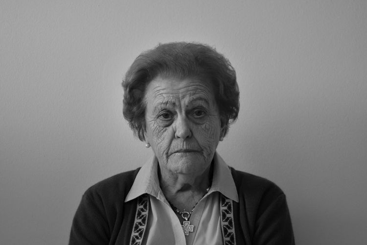 Close-up portrait of senior woman against white background