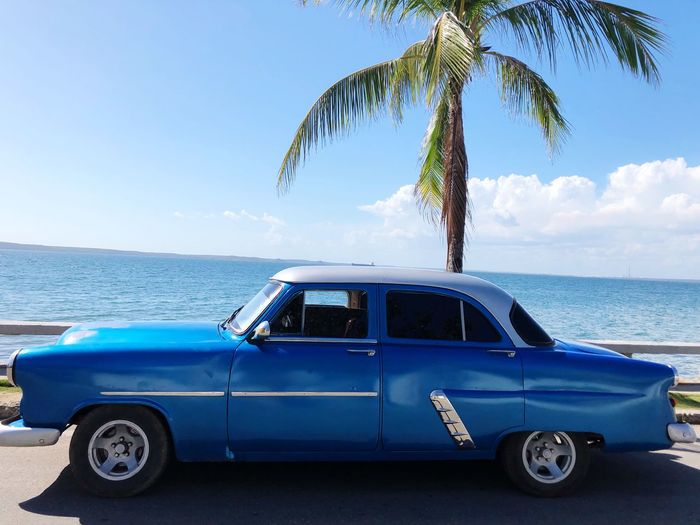 Vintage car on beach against blue sky