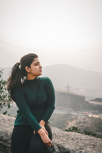 Young woman looking at mountain against sky