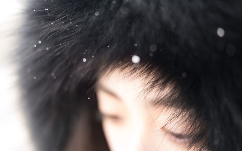 Close-up of woman wearing back fake fur during winter