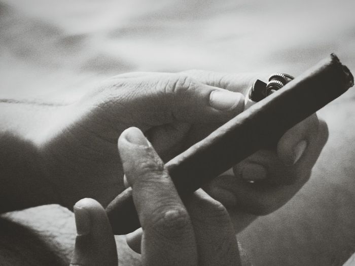 Cropped hand holding cigar and lighter