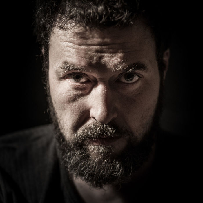 Portrait of serious mid adult man with beard against black background