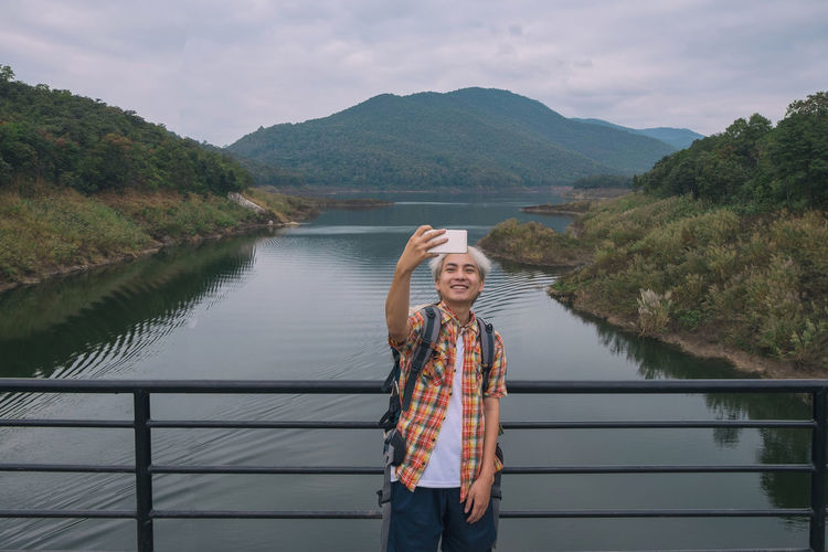 Man taking selfie while standing against lake