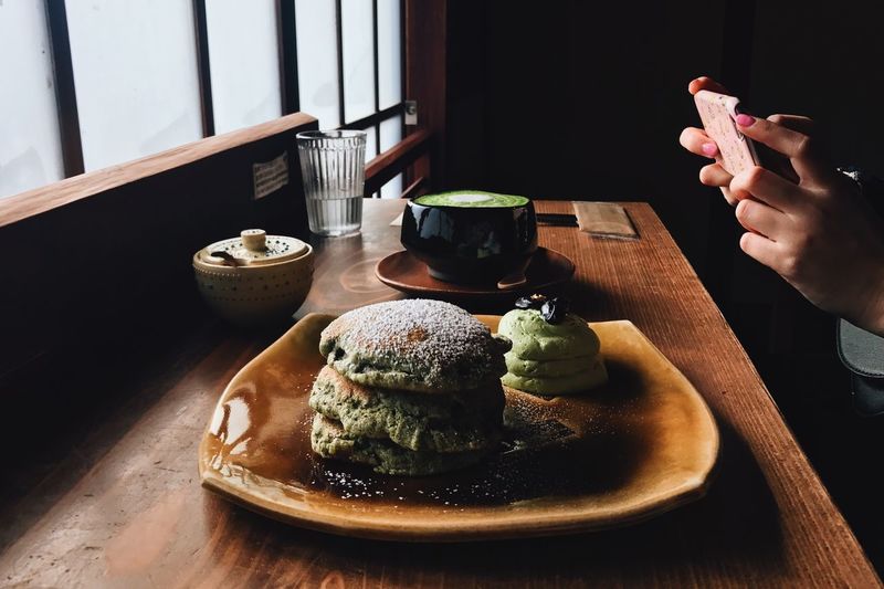 Cropped hands of woman photographing food in plate at restaurant
