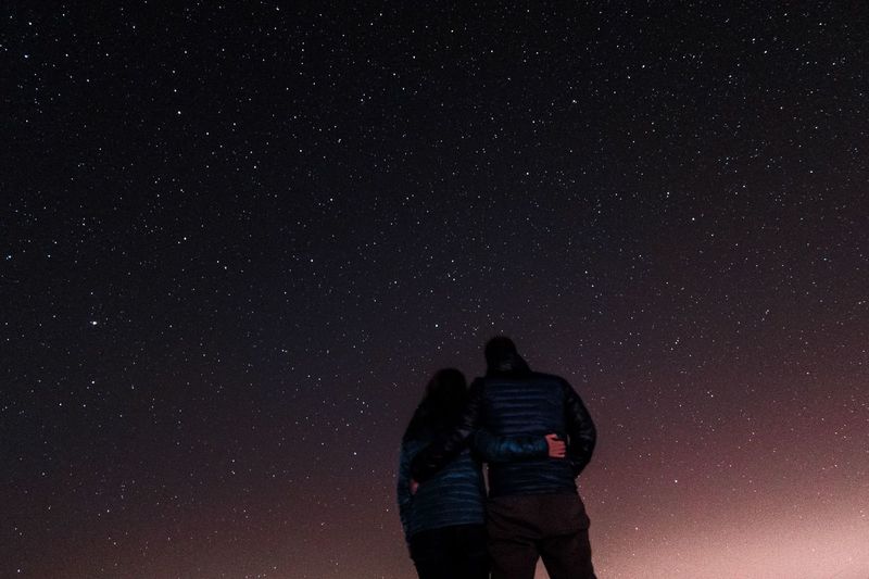 Low angle view of couple standing against star field