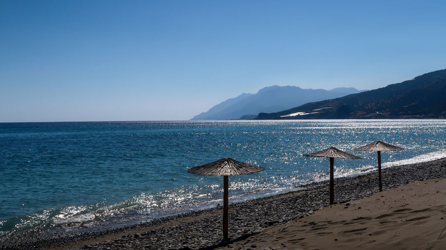Hay umbrellas on the beach and mountains far away - keratokampos, crete