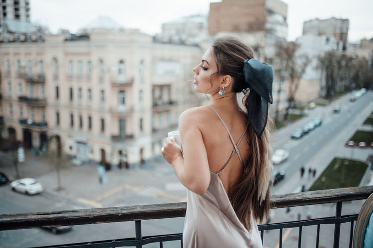 Young woman standing on railing in city
