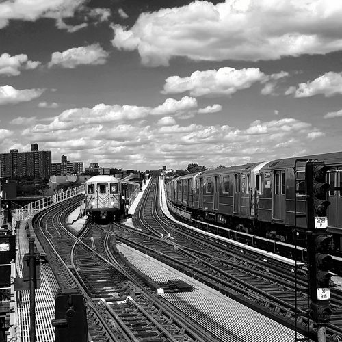 Trains on railroad tracks against cloudy sky