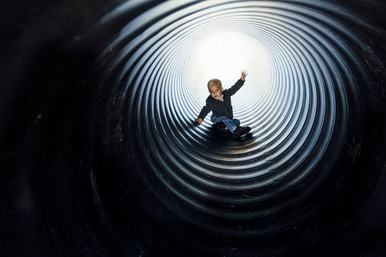Full length of boy sliding in slide at park