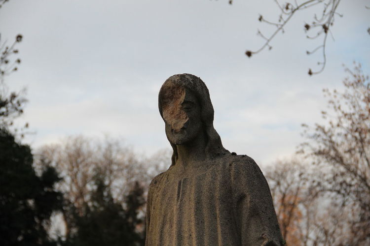 Low angle view of damaged statue against sky