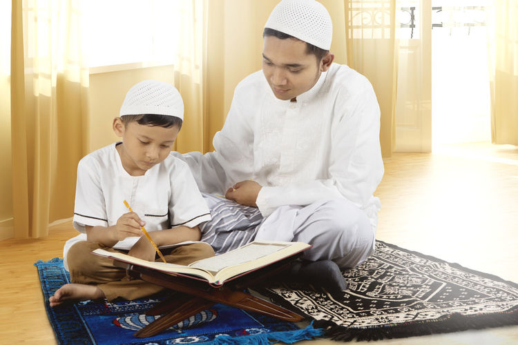 Father and son reading quran at home