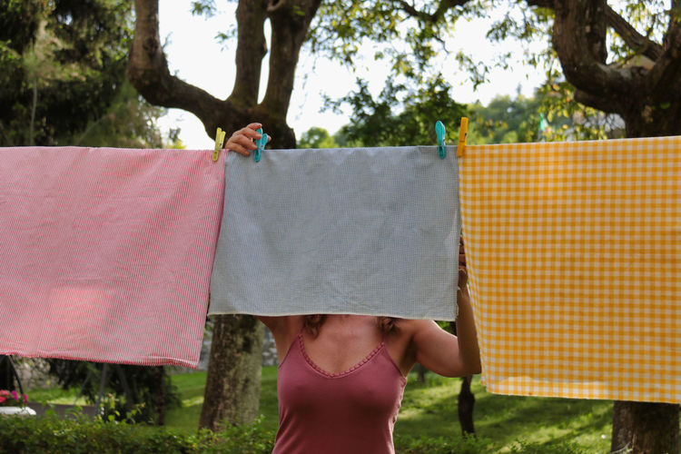 Midsection of woman hanging laundry on a thread in the garden
