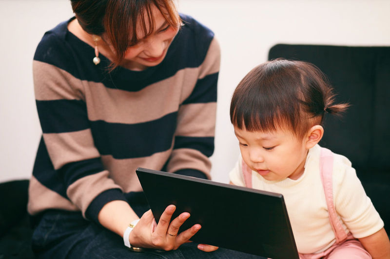 Mother with daughter using digital tablet at home