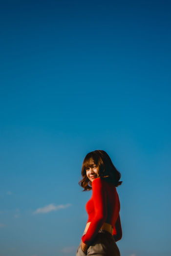 Portrait of woman standing against blue sky