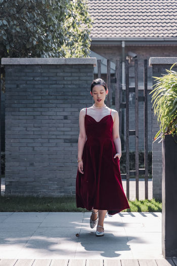 Portrait of young woman standing against built structure